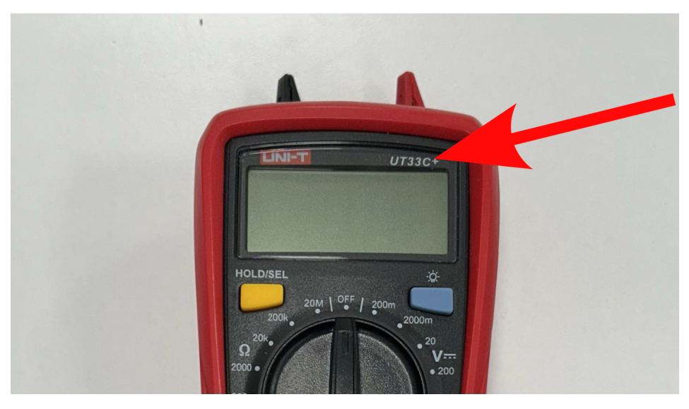 Photograph of a red Uni-T multimeter; a red arrow points to the model number printed at the top right of the display.