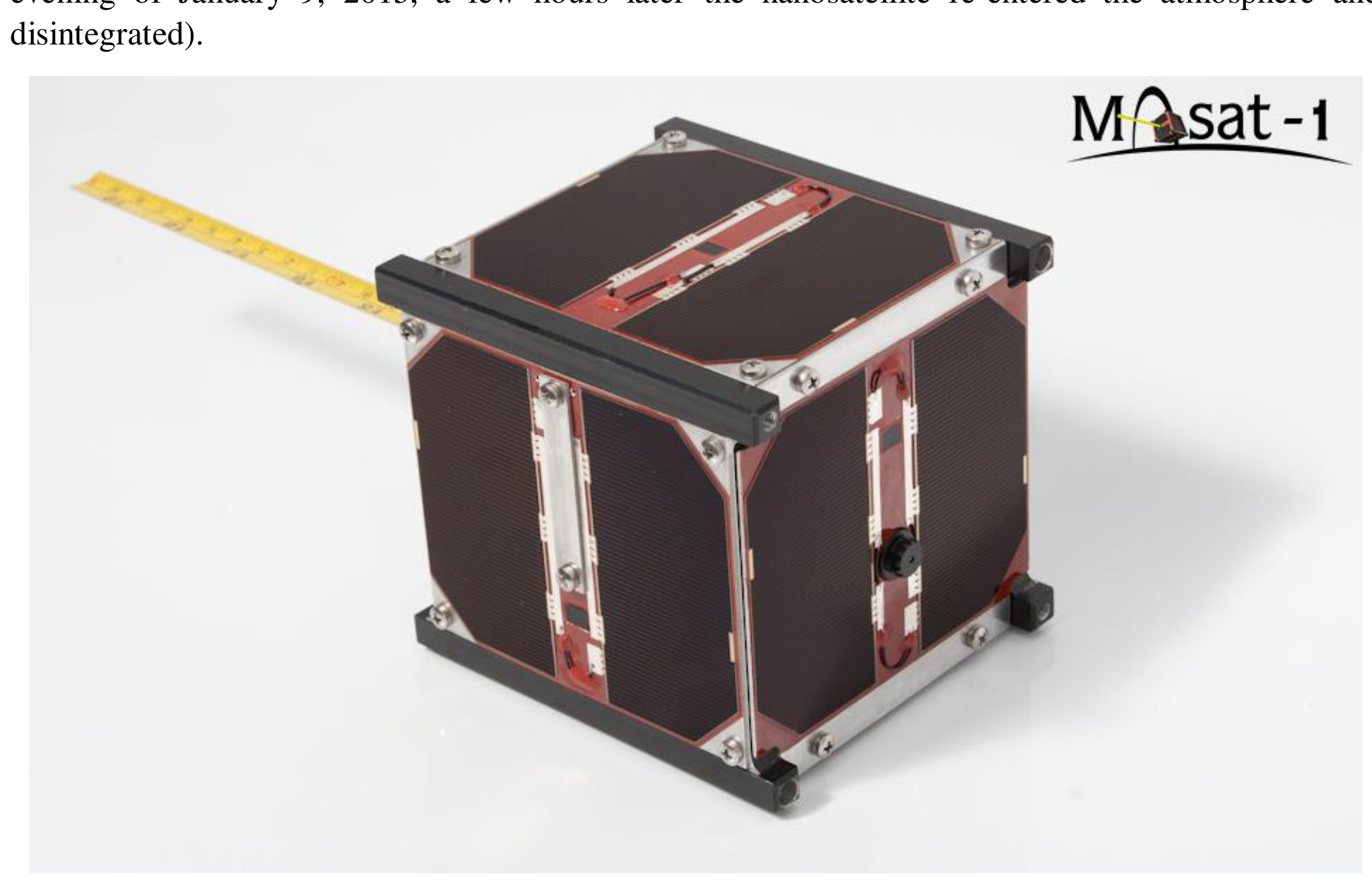 Photograph of the MASAT-1 cubesat: a 10 cm cubic aluminium satellite covered with dark solar cells, with a yellow measuring tape beside it and the logo 'Masat-1' in the upper right corner.