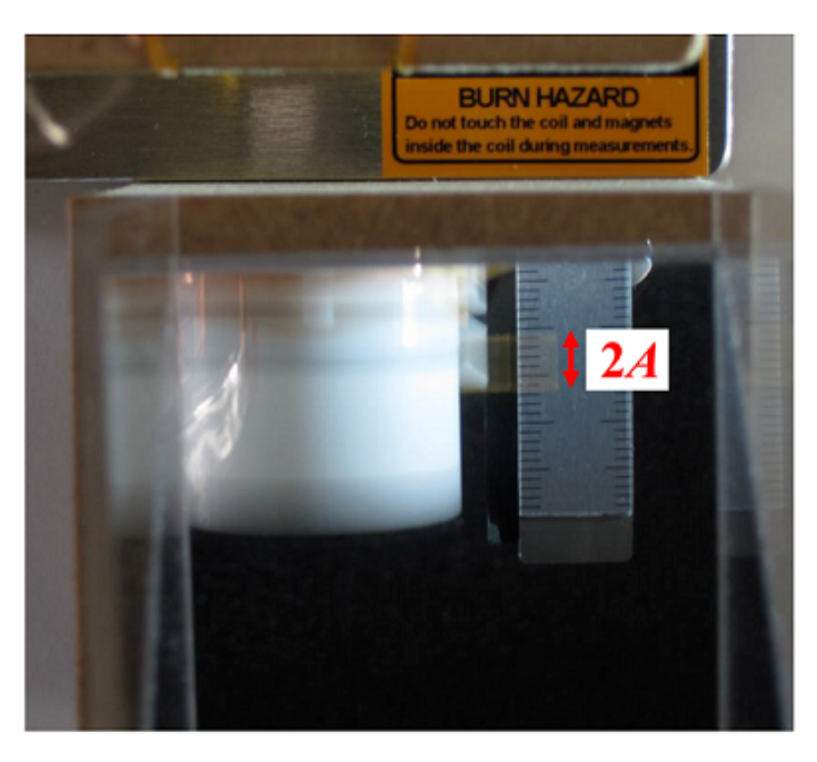 Photo taken through the mirror of the oscillating oscillator next to the scale, with a red brace spanning 2A and a BURN HAZARD caution label at the top.